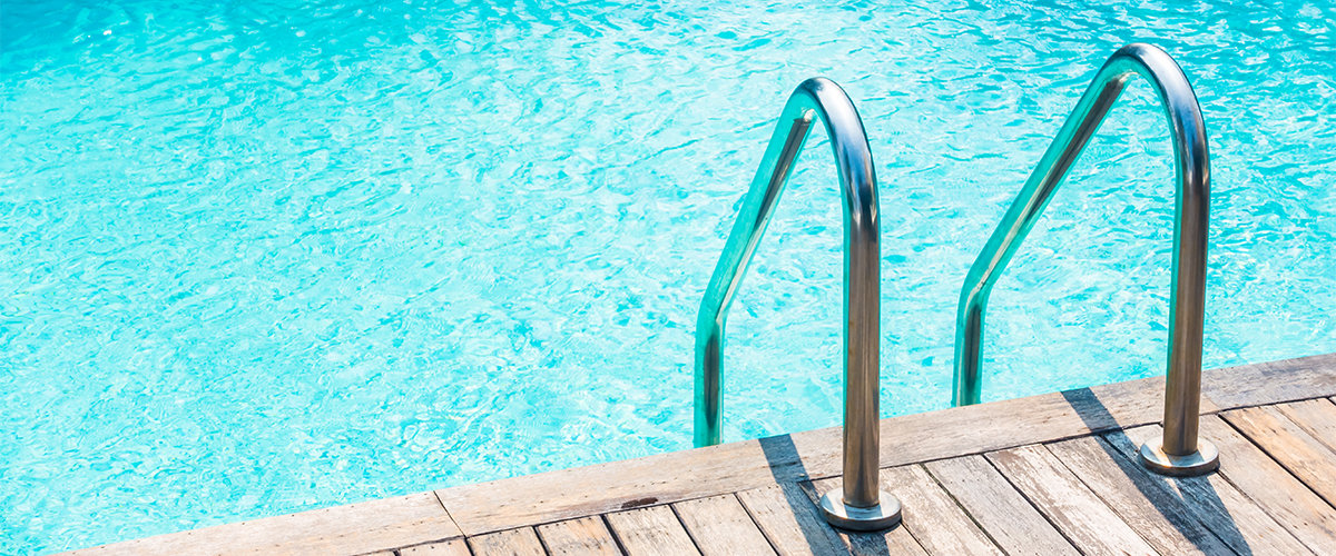 Ladder leading into backyard pool with blue water